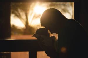 father holding new born infant with the sun setting in the background