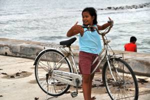 young filipino girl on a bike near the beach