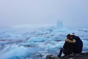 couple sitting on the edge of an iceberg