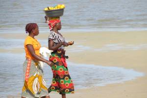 african women walknig carrying food on their head in baskets