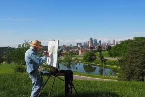 older man painting a scene on a sunny day