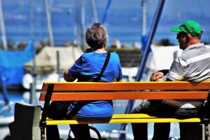 older couple sitting on a bench at a dock