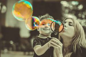 mom blowing bubbles with son who is happy and healthy