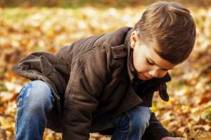 young boy playing in fallen leaves
